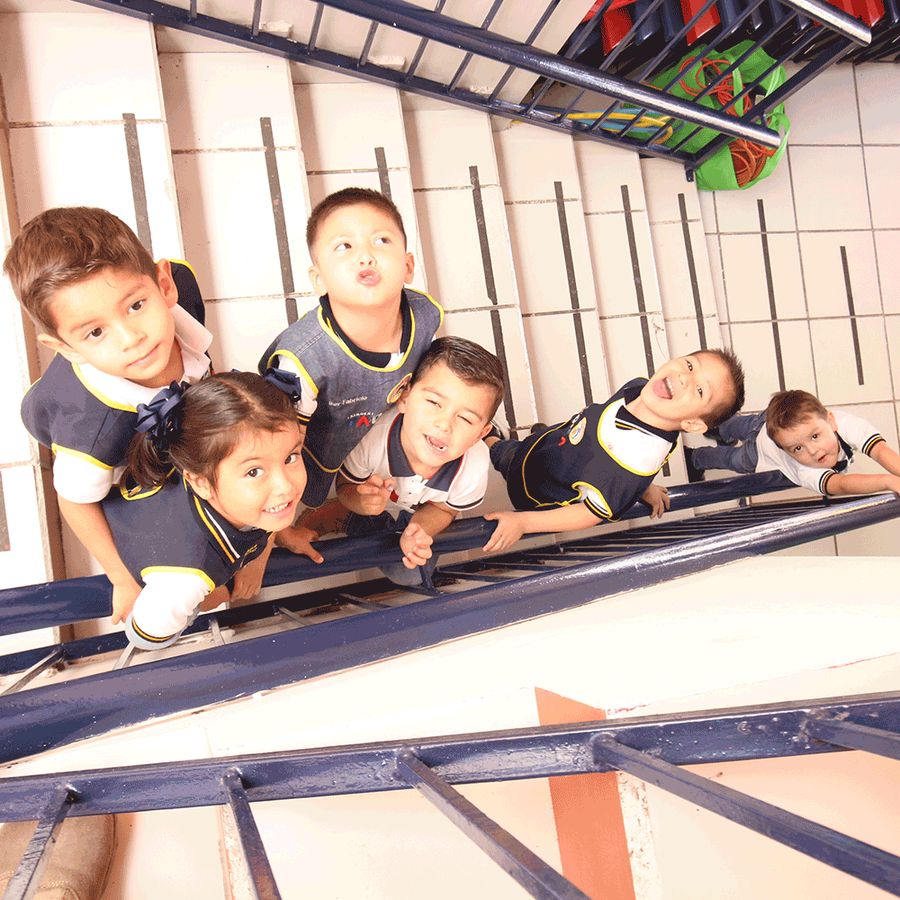 Grupo de alumnos de kinder sonriendo desde la escalera