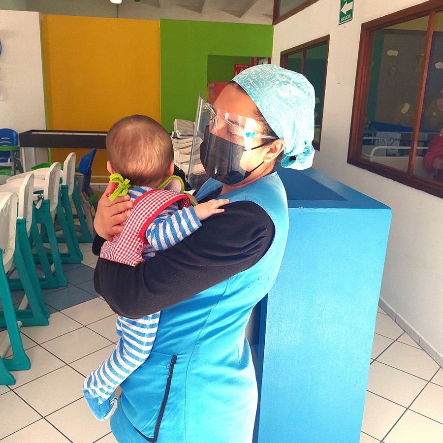 Enfermera de Guardería Pasitos cargando a un bebé